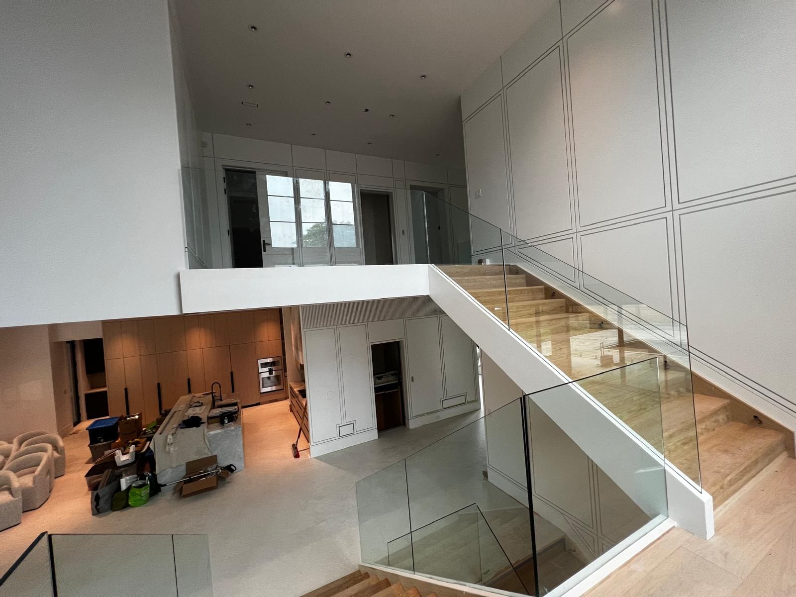 Frameless glass balustrade around a switchback stair in a double-height hall, installed by Reis Glass