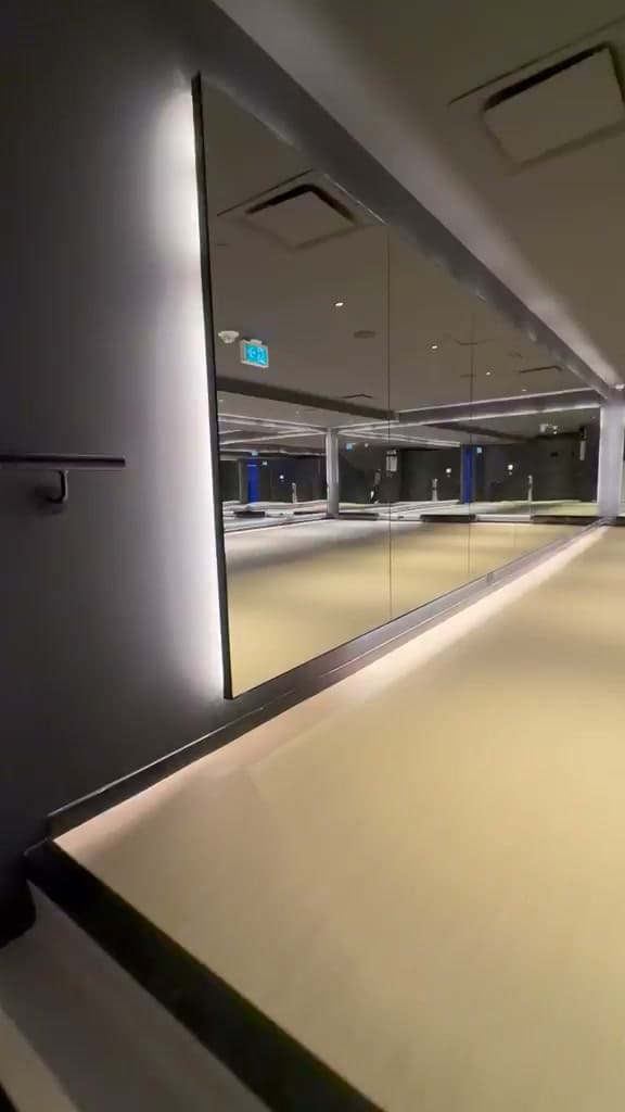 A mirror wall running around a commercial gym above a lit reveal